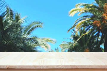 An empty wooden table on a blurry tropical background.