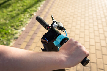 Hands of a young man holding an electric scooter close-up. Ecological transport