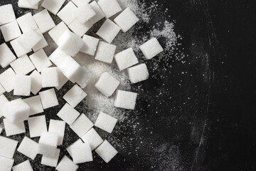 Refined sugar in cubes on a black background. View from above