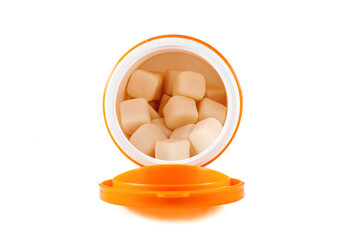 Gum in a bottle on a white background. Chewing gum in the form of cubes in an open jar. Close-up