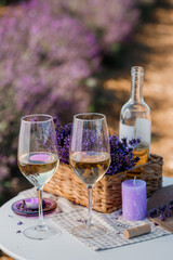 Two Glasses of white wine and bottle in a lavender field in Provance. Violet flowers on the...