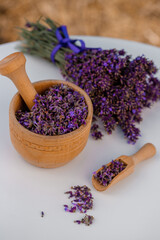 Obraz na płótnie Canvas Wooden bowl with dried lavender on field background. Flower herbal tea drink. Aromatherapy, medicine ingredient. Calming beverage