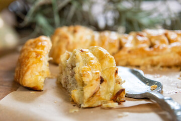 Two elongated chicken pies with golden pastry and a luxurious filling, cut into slices served alongside decorative plants