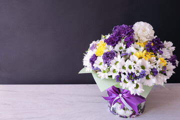 Bouquet of autumn flowers in a box with a bow. Floral arrangement on a black background. A postcard to congratulate you on your birthday, the beginning of the school year or other holidays. 