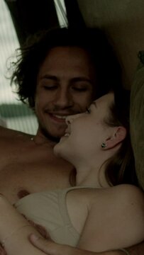 A young couple in love having a romantic moment, cuddling and conversing in bed inside a camper