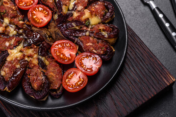 Fresh eggplant baked with minced meat, spices and herbs on a black plate