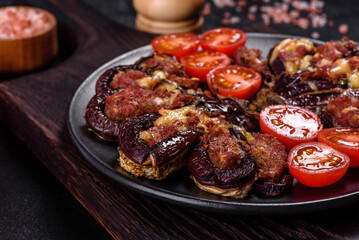 Fresh eggplant baked with minced meat, spices and herbs on a black plate