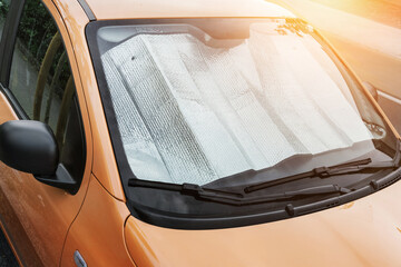 Automotive metallic reflector is covering windshield inside of car in hot summer day - Powered by Adobe