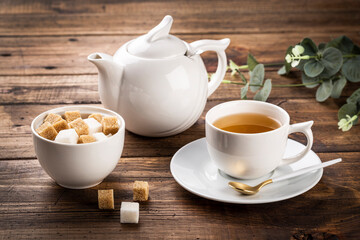 tea concept mockup, white cup of tea and teapot, sugar in white bowl with space for a text on light background.