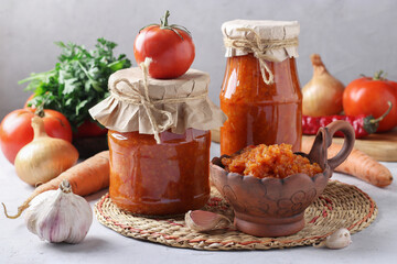 Homemade vegetable caviar from carrots, peppers, garlic and tomatoes in bowl and glass jars on...