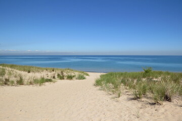 grassy sand dune trail to great lake with sky