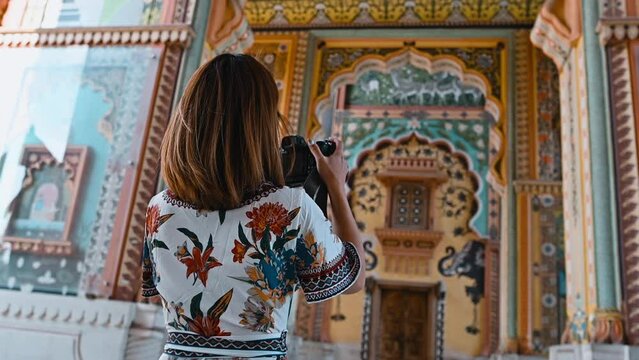 Asian woman in colorful dress using camera photographing the art of Patrika gate The ninth gate of Jaipur in Rajasthan India
