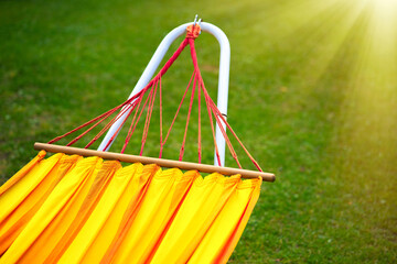 Orange hammock made of fabric on a background of green grass. Relaxation and sleep in the fresh air.Rest after work. Relax in nature.