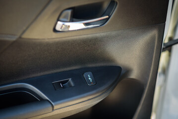 Obraz premium Car door control right rear panel. Leather new car interior. Car inside door chrome handle. Window lifter control. Armrest with seat heating adjustment button. Window open and close buttons. Door trim