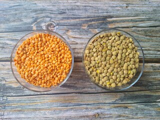 Lentils: orange and green in bowls on wooden table, top view. Culinary lens.