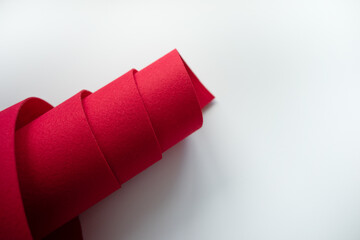 A roll of red felt fabric on a white background.Sale of fabric. Red material for sewing and crafts.