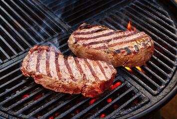 Barbecue dry aged wagyu roast beef steak grilled as close-up on a charcoal grill with fire and smoke