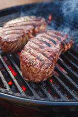 Barbecue dry aged wagyu roast beef steak grilled as close-up on a charcoal grill with fire and smoke