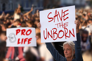 Protesters holding signs Save the unborn, Pro Life. People with placards against abortion rights at protest rally demonstration. Concept image. - 521094262