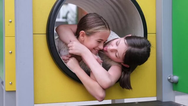 two pretty teen girls playing on a modern playground in identical clothes. sister, bffs. sisterhood, friendship