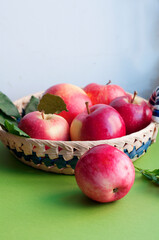 Fototapeta na wymiar Fresh ripe red apples in a straw plate on a green background