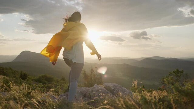 The girl climbs to the top of the mountain at sunset and raises her hands to the top. A woman gives a sign of freedom and victory in a beautiful mountain landscape. High quality 4k footage