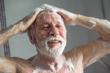 Senior man taking a shower in the bathroom in the morning