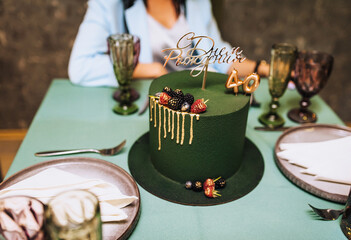 A beautiful green cake decorated with raspberries stands on the table with a sign inside in honor...