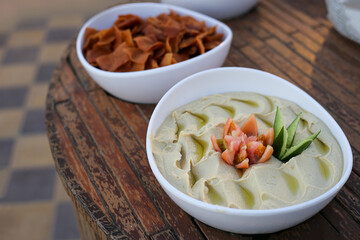 Hummus in white plate on wooden table. Arabic dish