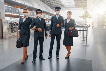 Airliner pilot and air hostess standing in airport during the COVID pandemic