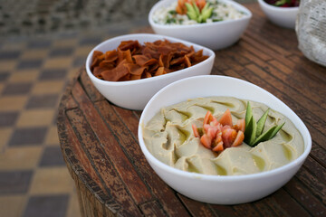 Hummus in white plate on wooden table. Arabic dish
