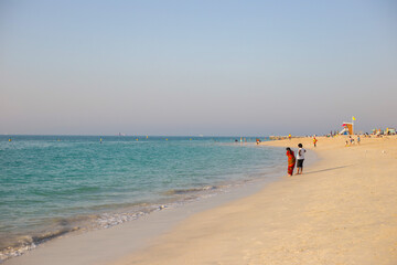 People walk along the beach in Dubai at sunset. Summer walk