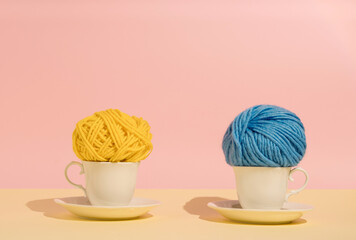 Cups with blue and yallow ball of yarn for knitting. Minimal concept for socializing with coffee,...