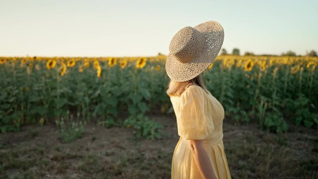 Attractive woman in old-fashioned dress walking alone near sunflowers field. Vintage fashion, amazing adventure, countryside, rural scene, natural lifestyle.