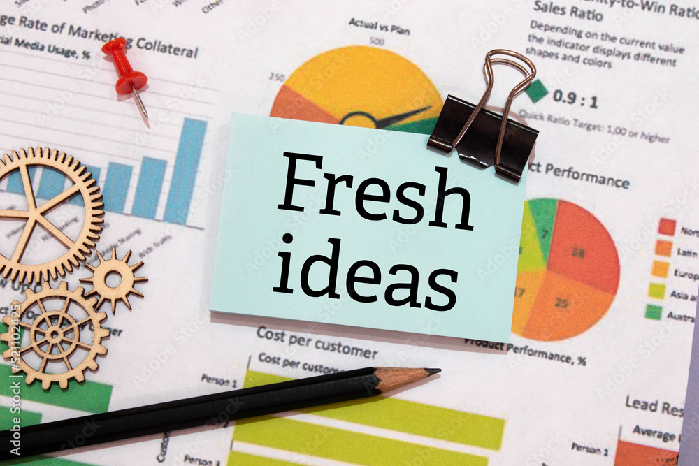 Poster paper and a white notebook with the text fresh ideas on the desktop.