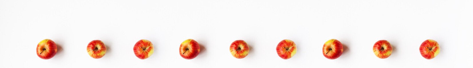 Banner flat lay top view of set of red yellow apples are laid out in a straight line on white background. Healthy organic autumn food and still life concept with copy space