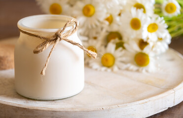 Aroma candle with Chamomile flavour on table, home aroma oils in bedroom. Healthy lifestyle and interior elements