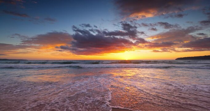 Ocean beach sunrise with color sky clouds and sun rays over sea waves, 4K video landscape