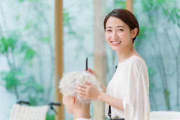 白髪の女性の髪を切る美容師のポートレート