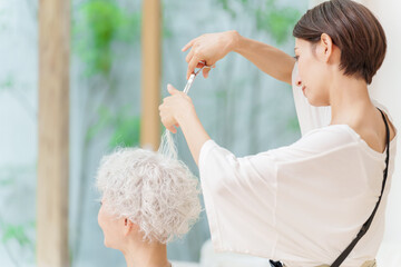 白髪の女性の髪を切る美容師