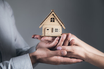 Hands of family couple holding a model of a house