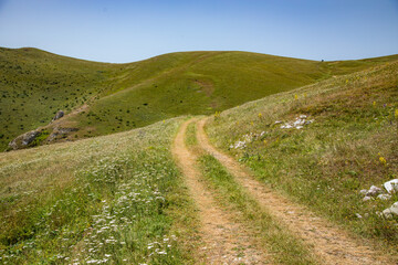 Naklejka na ściany i meble Mountain road in spring ridge landscape.