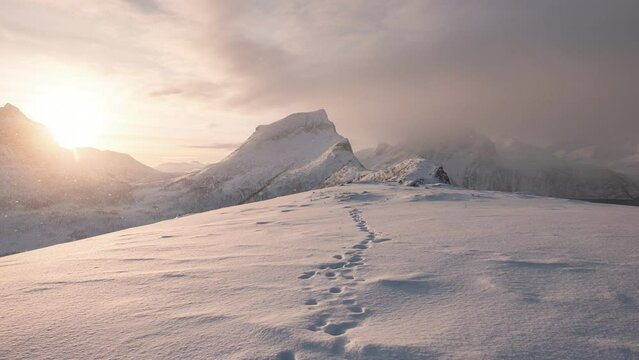 Sunrise over snowy mountain peak with footprint on winter in the morning at Segla mount, Senja island, Norway
