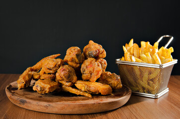 the photograph shows some delicious chicken wings accompanied by potatoes, beer