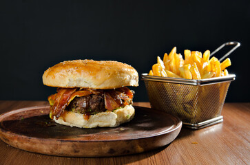 the photograph shows a delicious hamburger accompanied by french fries