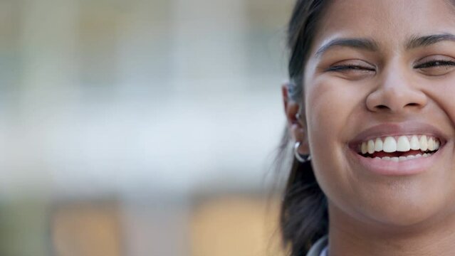Closeup face portrait of a happy woman smiling, laughing and looking cheerful while standing outside against blurred background for copy space. Head of a young, cute indian female with kind features