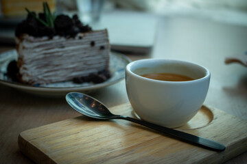 Hot coffee in white cup with black spoon on wooden plate
