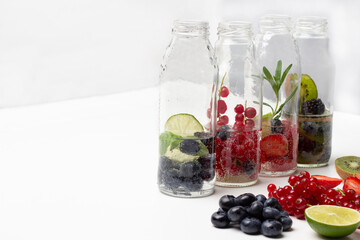 Fototapeta na wymiar Sparkling red currants, strawberries, blueberries and blackberries water in glass bottles.