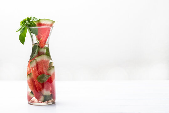 Sparkling watermelon water with green basil in glass jar.
