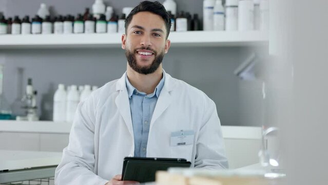 Happy health care professional doing research on a tablet in a modern lab. Confident scientist feeling positive about a breakthrough or discovery, searching for a cure for diseases